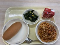 京都市修学院第二小学校4月15日の給食。食器が△に並べられている。左には小型コッペパン。右にはスパゲティのミートソース煮。その2つのちょうど真ん中の上にはほうれん草のソテーが置いてある。スパゲティのミートソース煮の上には牛乳が置いてある。