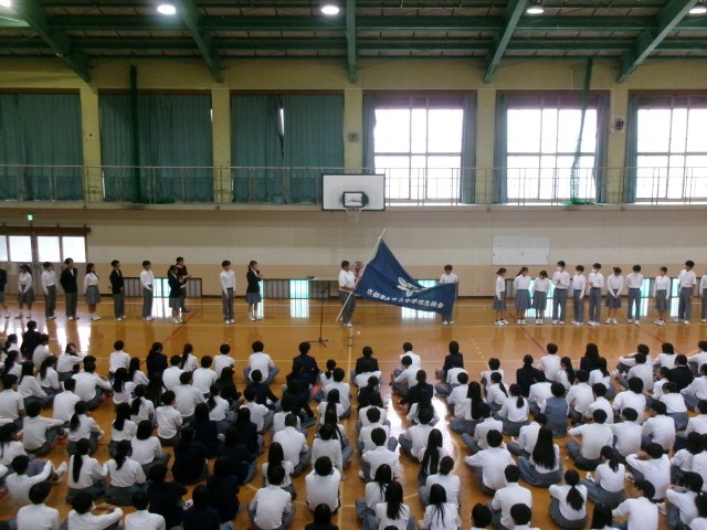 旧生徒会本部役員から新生徒会本部役員へ生徒会旗を引き渡す様子